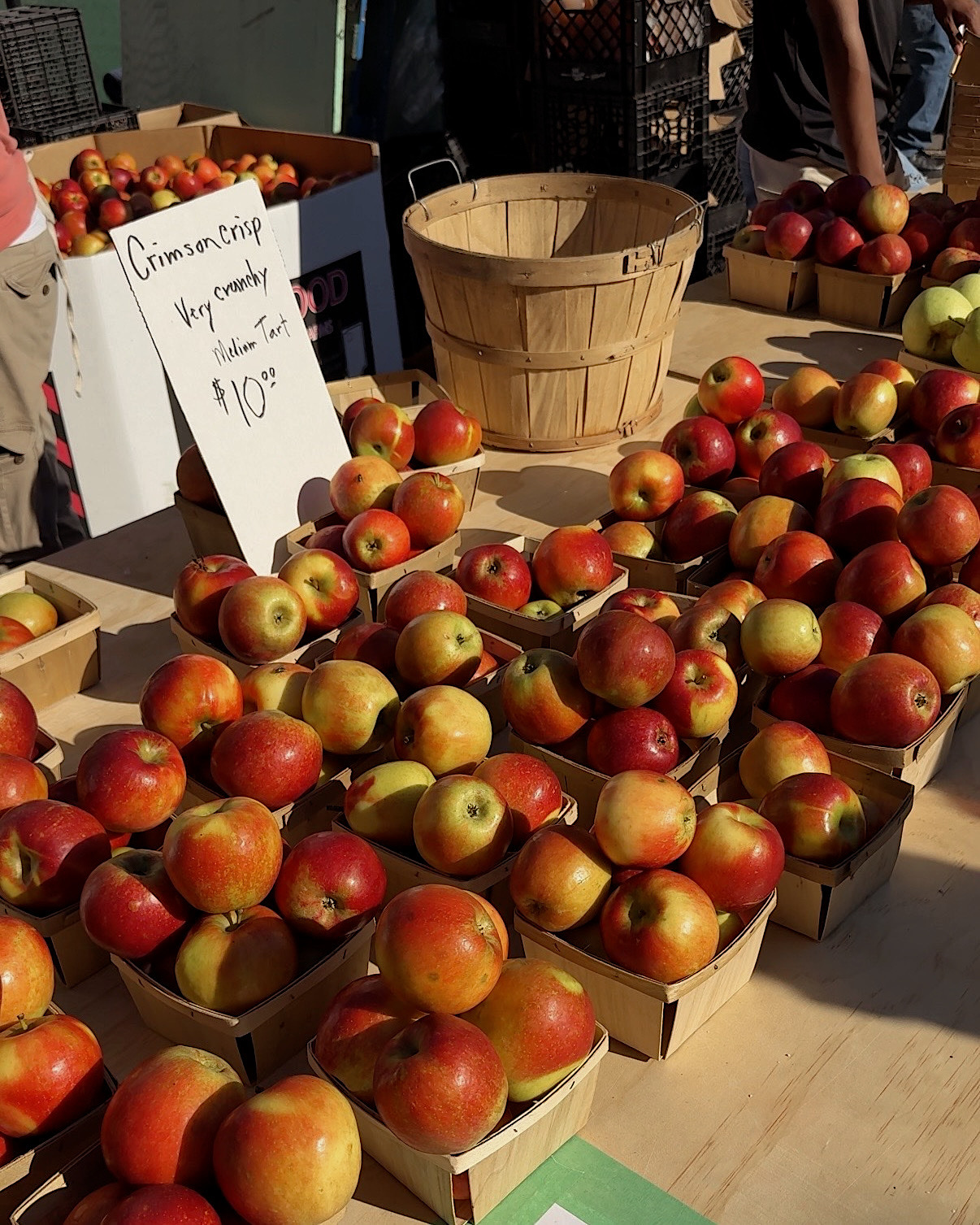 Crates of red and gold apples at a sunny market stall